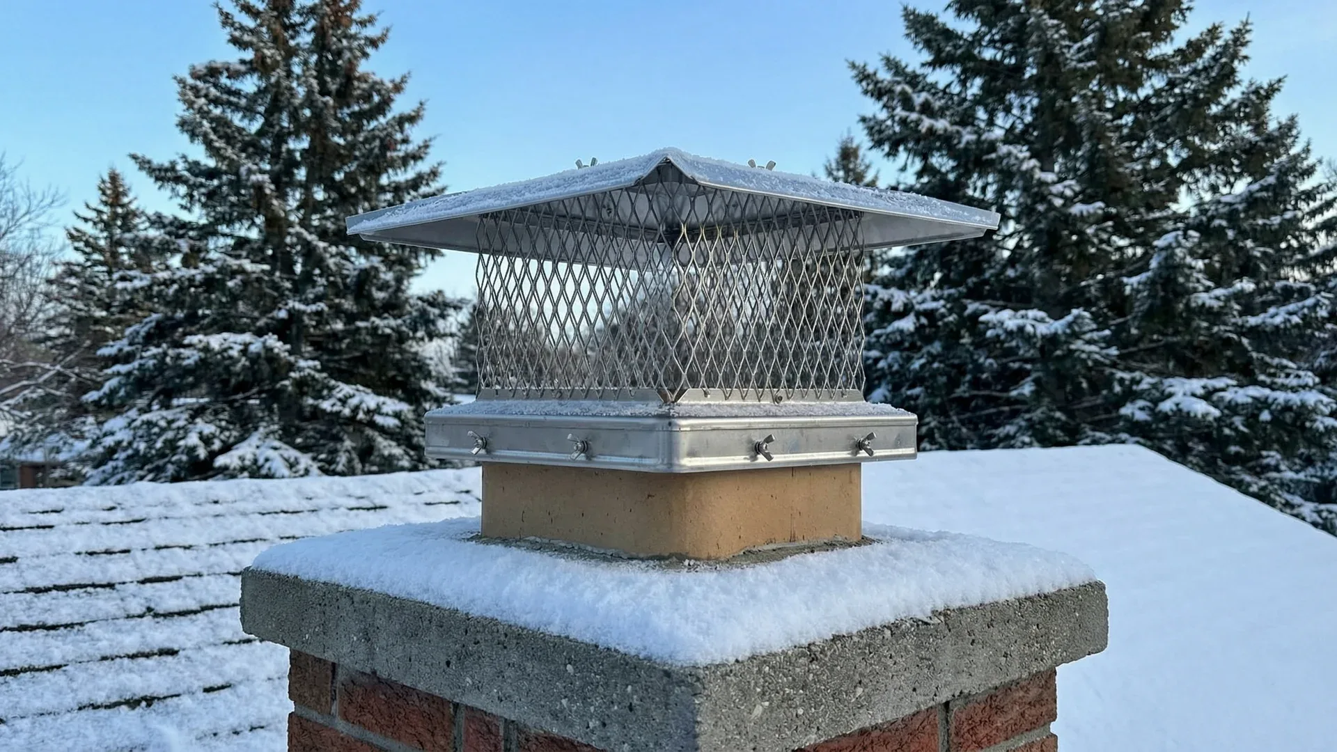 Stainless steel ChimCare chimney cap on a brick chimney in winter
